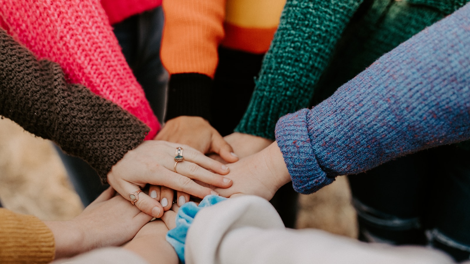 Several hands stacked together in a gesture of teamwork and shared purpose