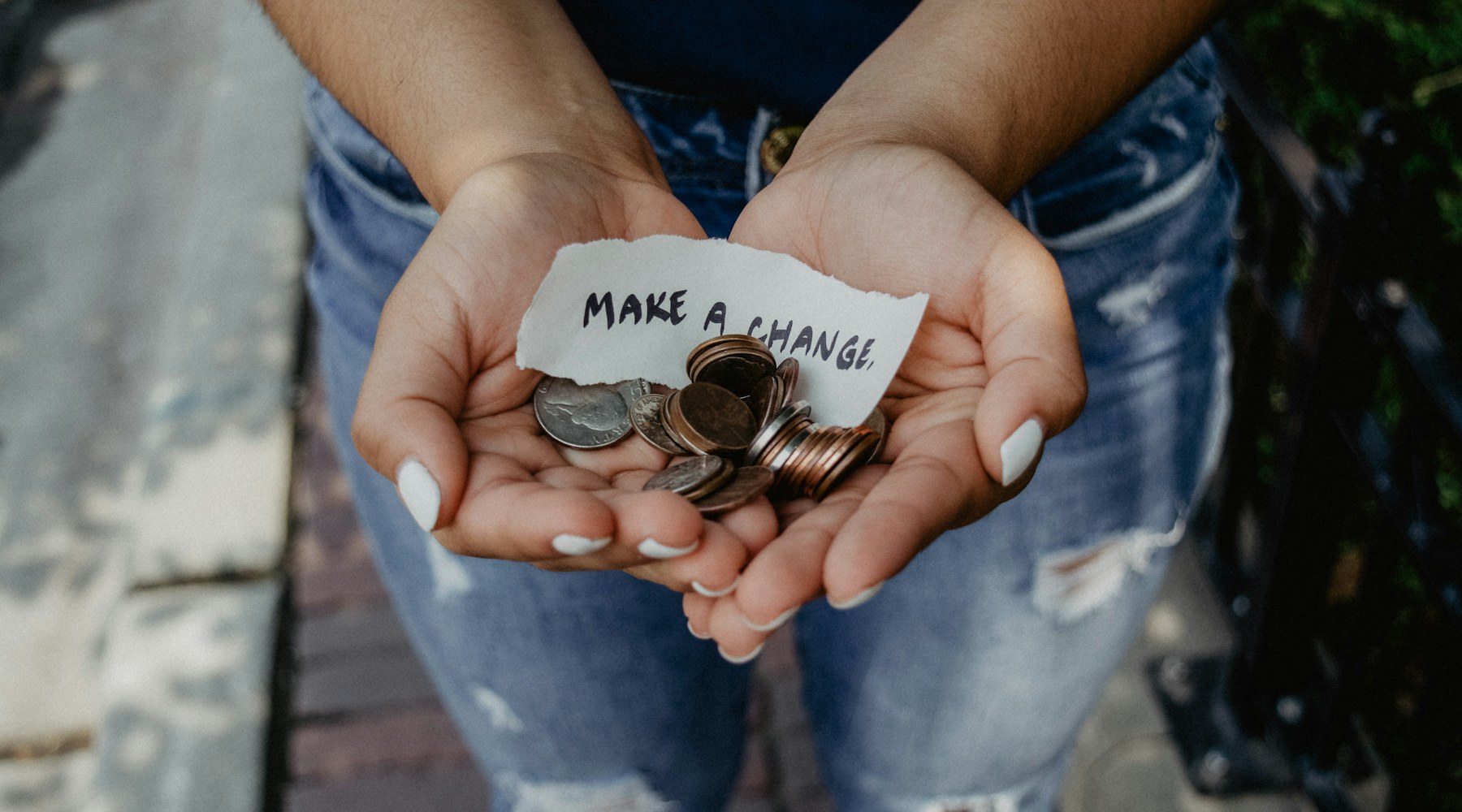 Cupped hands holding coins and a note that reads Make a Change